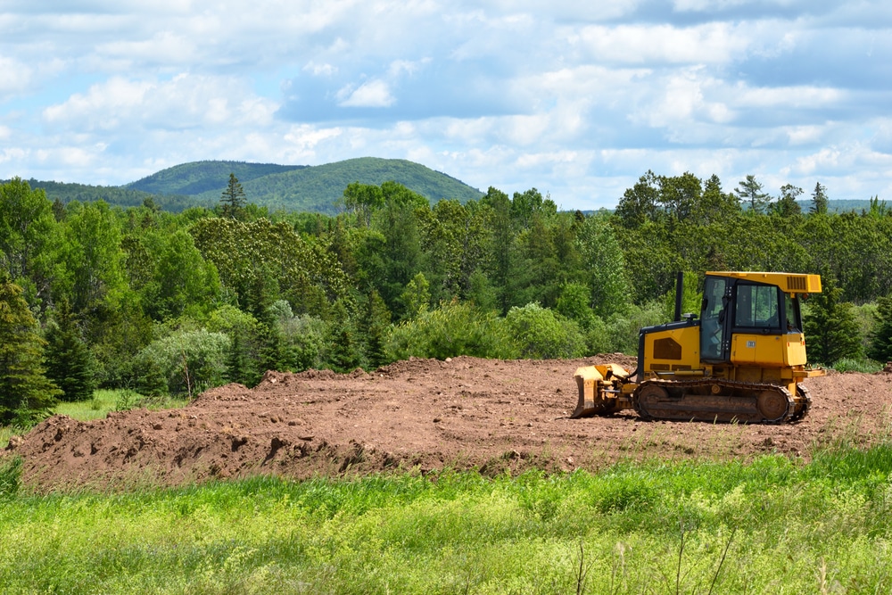 Land clearing equipment working on a prepared site in Ottawa, with a backdrop of trees and hills, showcasing ZZ Chop Tree Care's professional land clearing services.